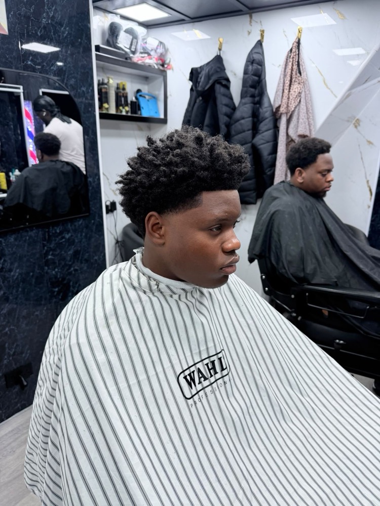 Side view of a high curly top with a clean taper fade and sharp line-up.
