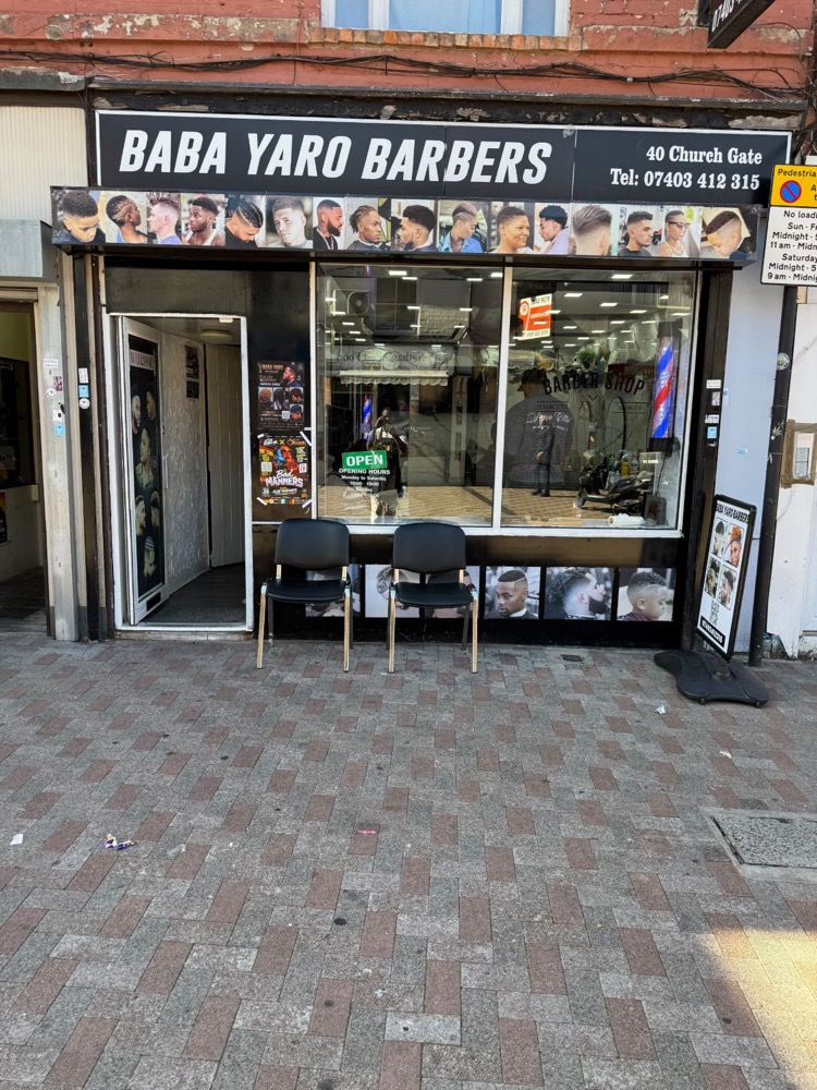 The shopfront of Baba Yaro Barbers at 40 Church Gate, with two chairs outside.